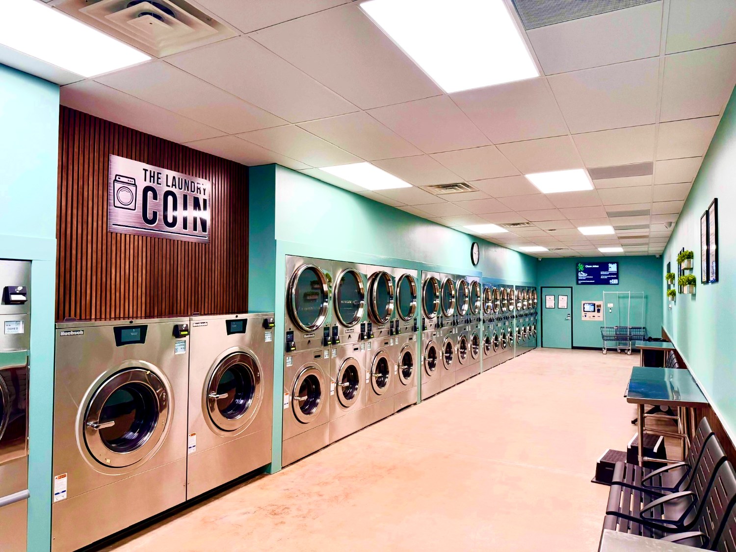 The aisle of new washers and dryers inside The Laundry Coin, under the store sign
