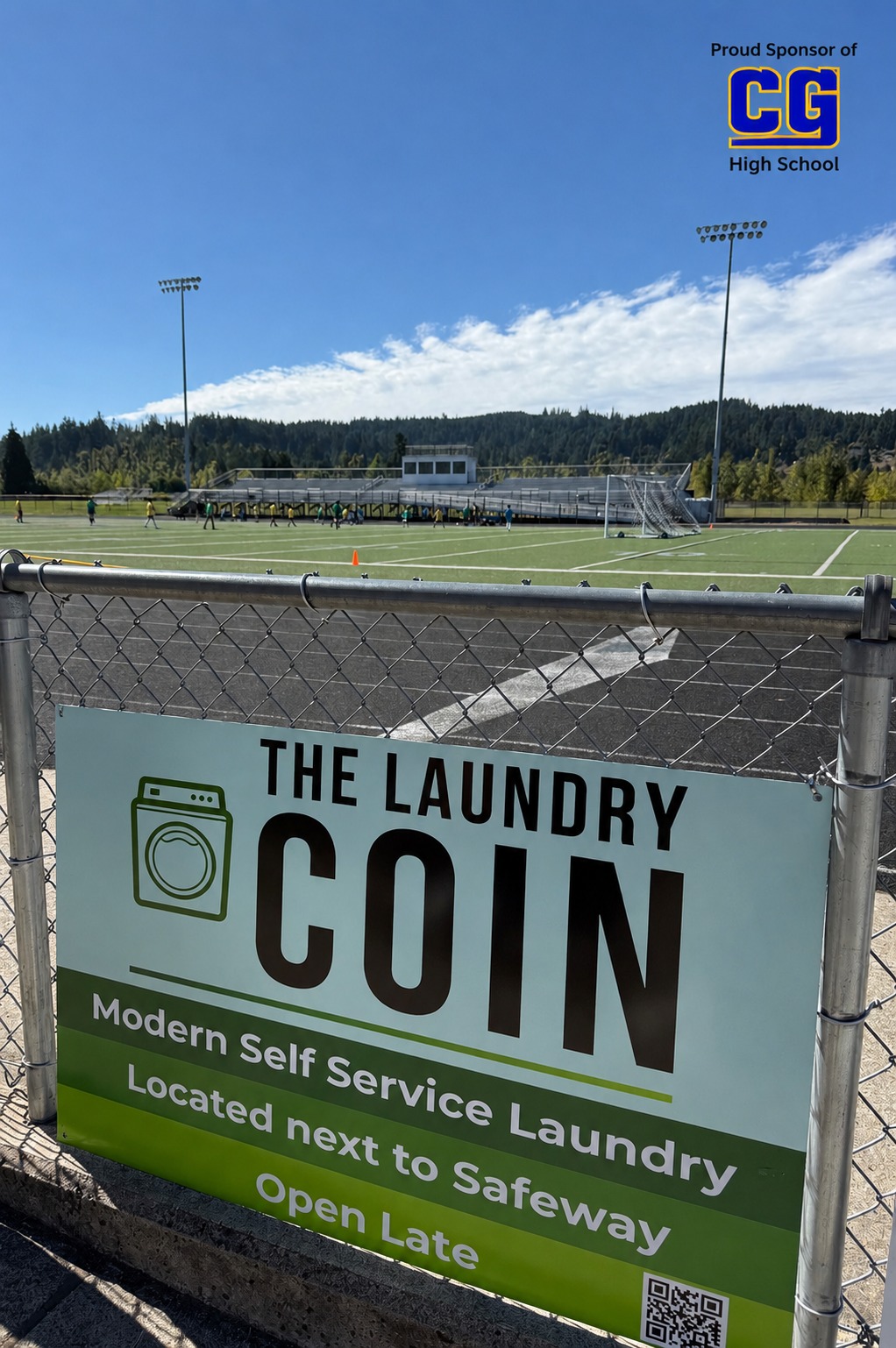 The Laundry Coin sponsor banner on the fence at the Cottage Grove High School field